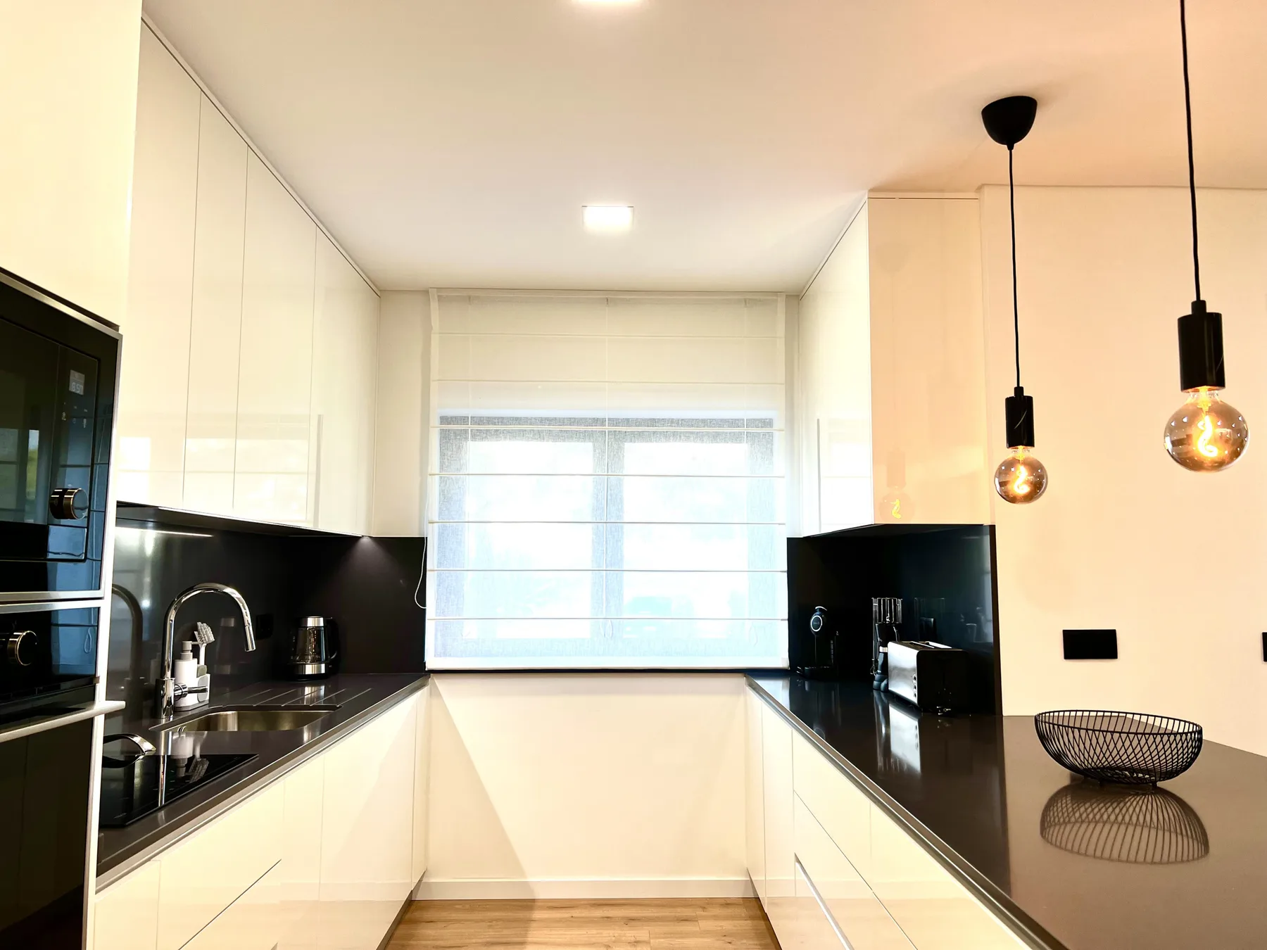 Una cocina moderna y luminosa con encimeras negras y una ventana grande.