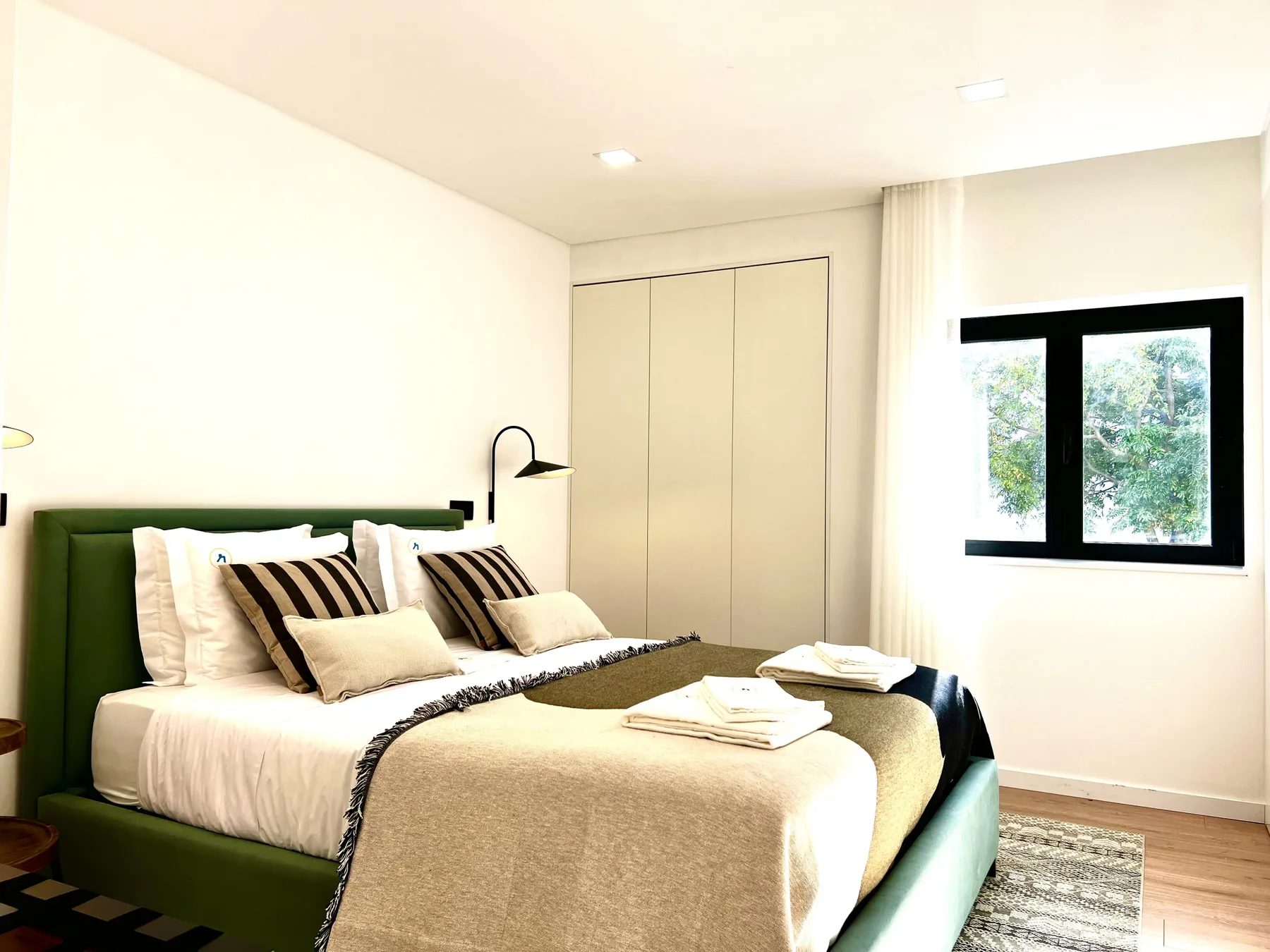 Un dormitorio con una cama, una lámpara de pared y una ventana.