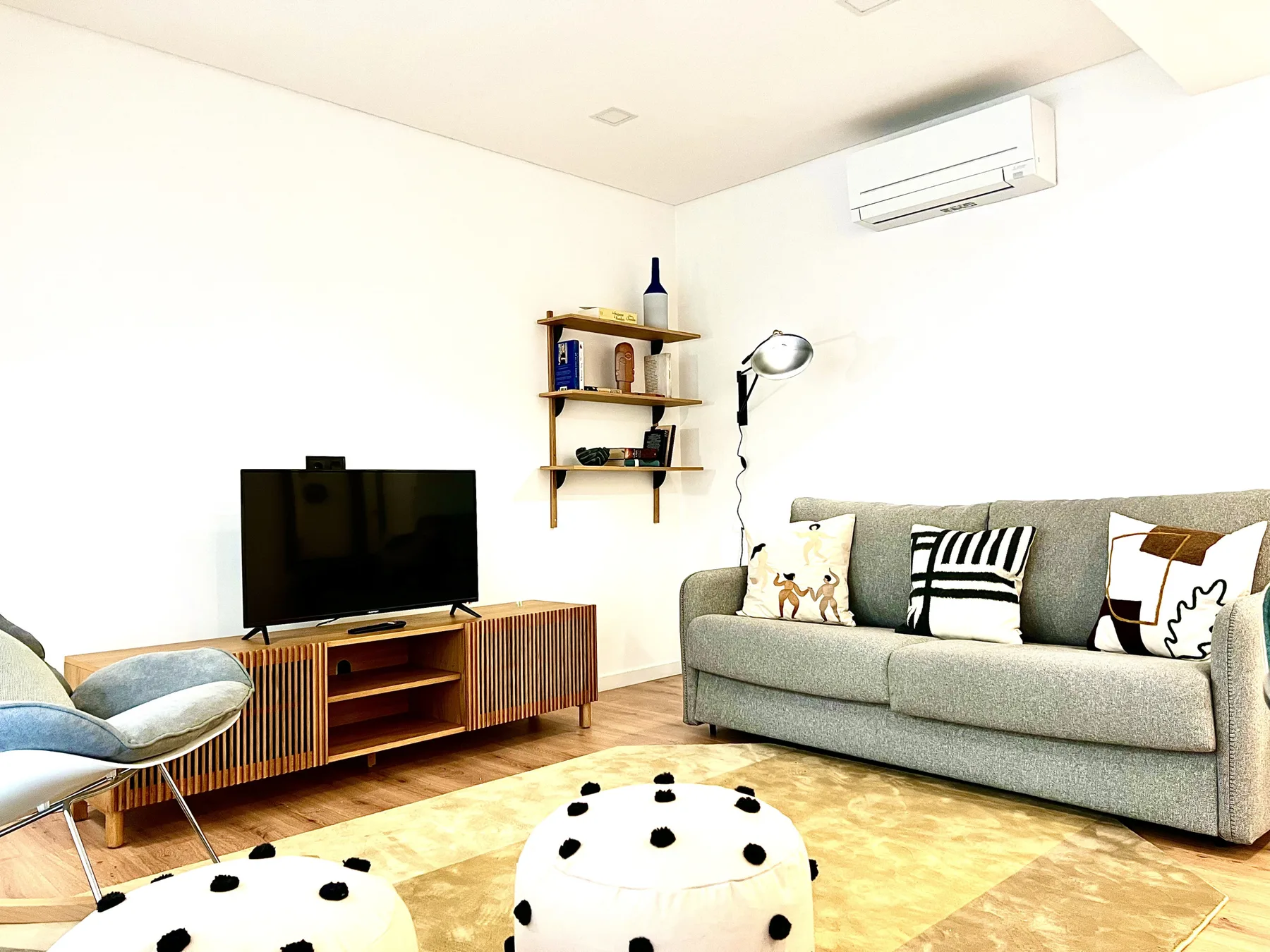 Una sala de estar con televisor, asientos y una alfombra estampada.