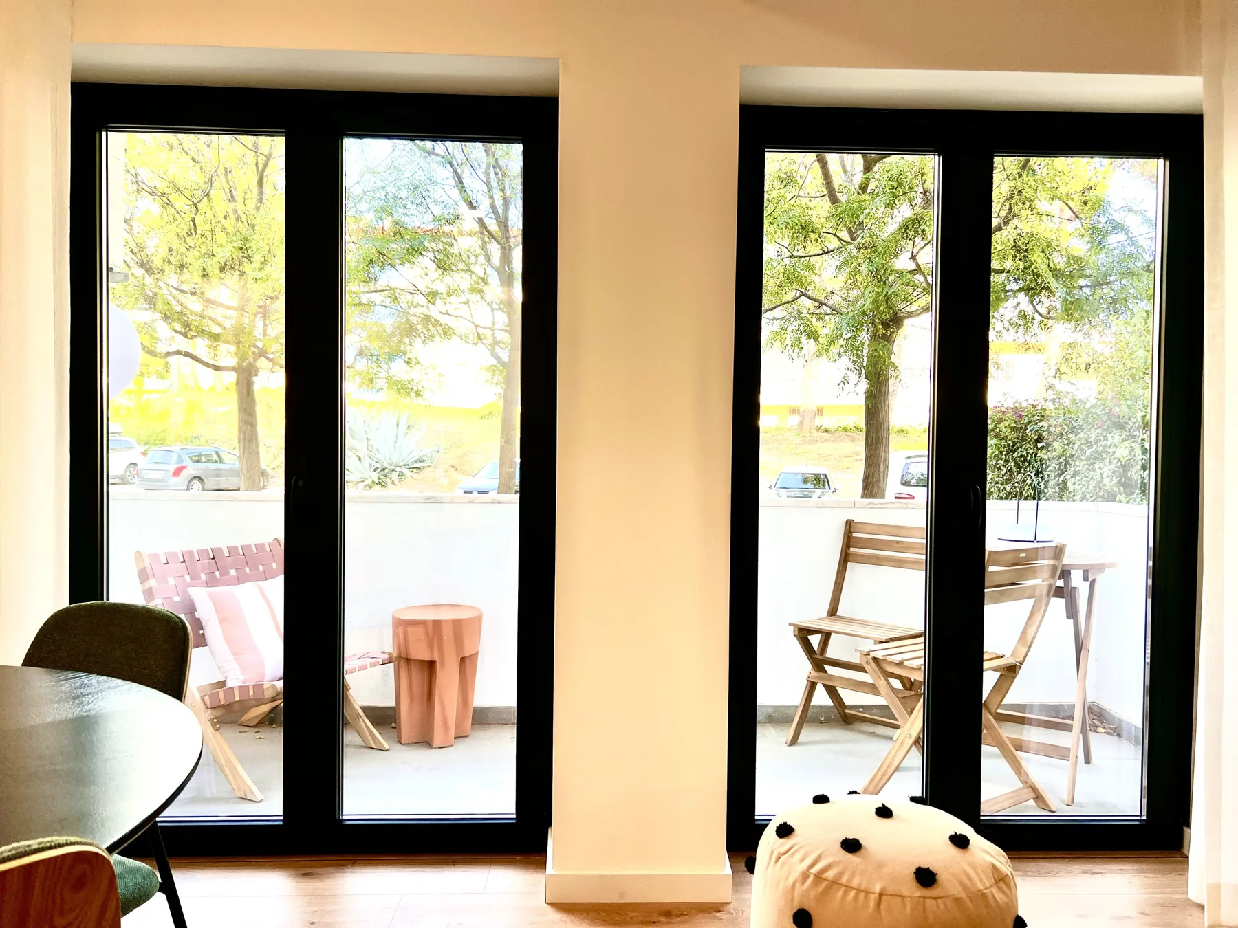 Una sala luminosa da a un balcón con asientos al aire libre y árboles al fondo.