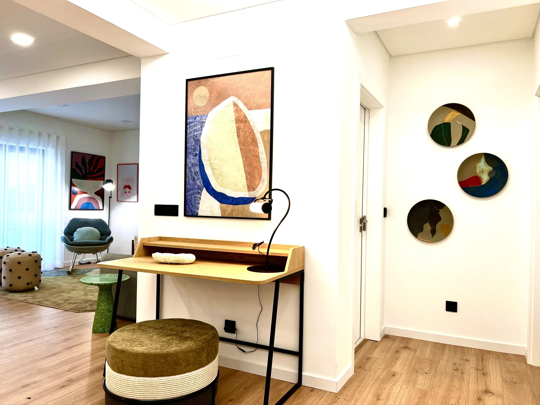 Un interior luminoso con un escritorio de madera, arte abstracto y una zona de estar.