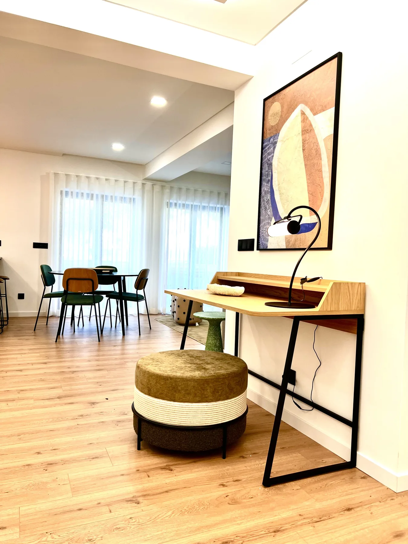 Una luminosa zona de comedor y trabajo cuenta con una mesa, un escritorio y grandes ventanas.