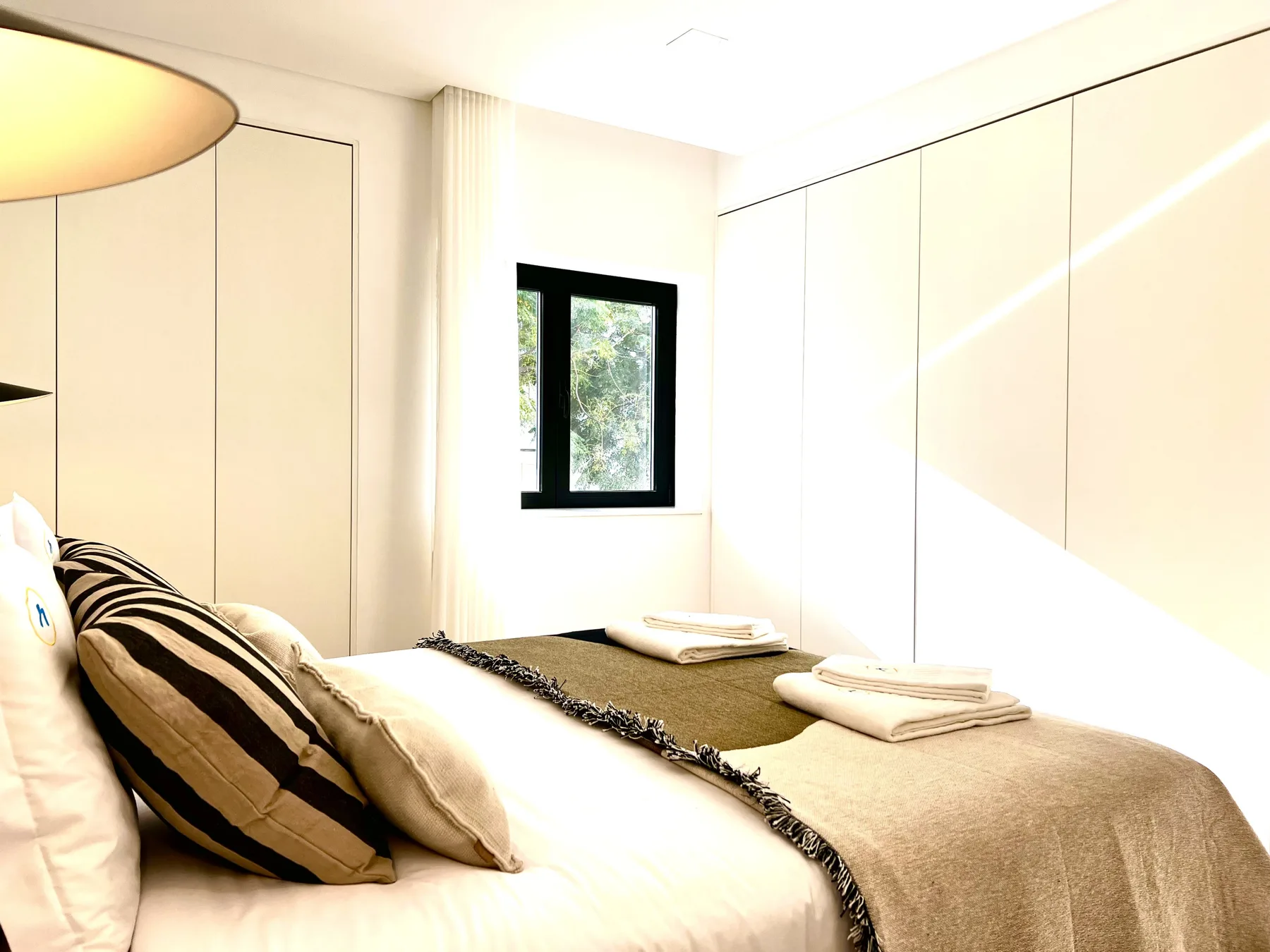 Un dormitorio luminoso con una cama hecha y una ventana pequeña.