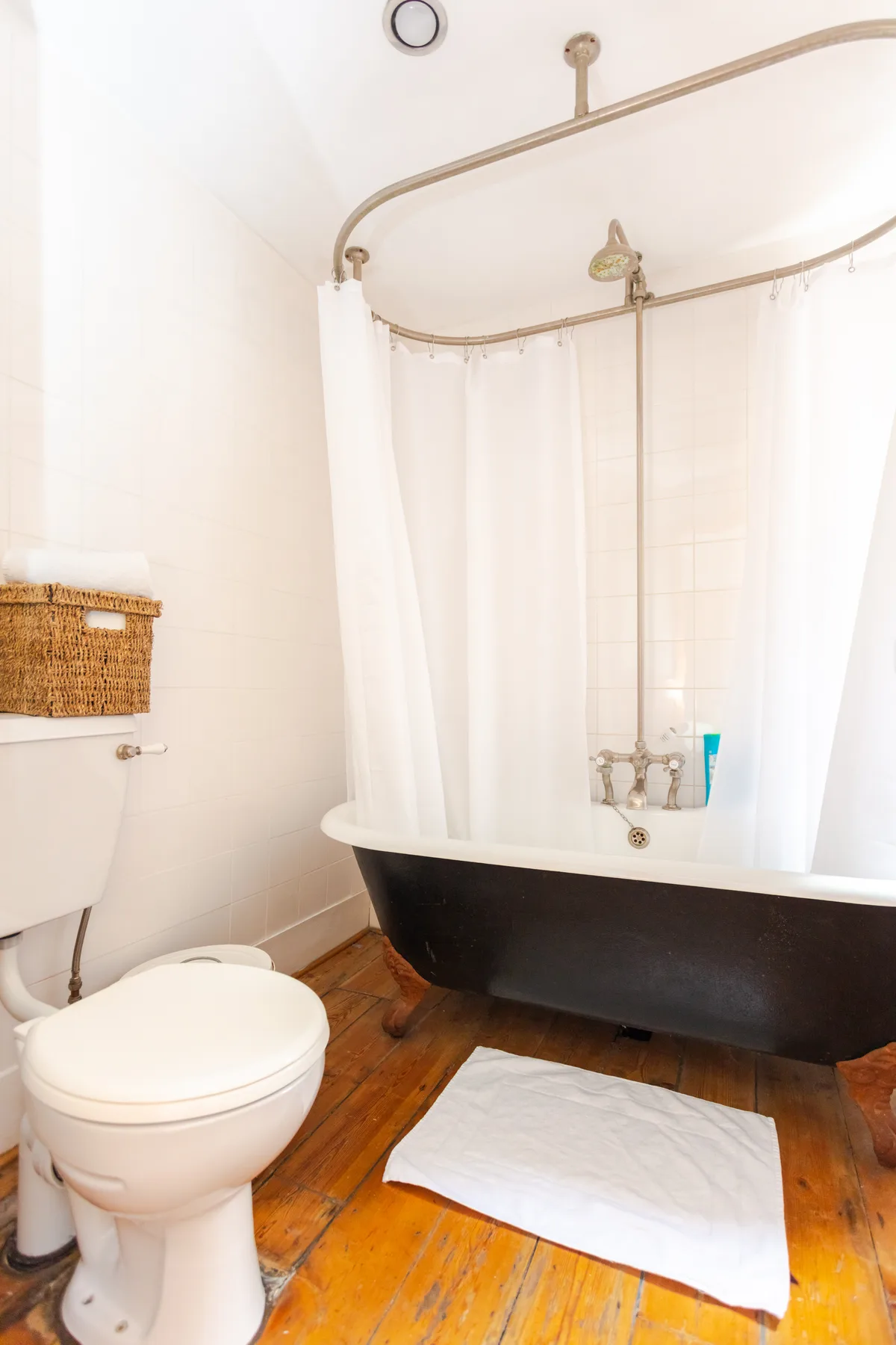 A bathroom with a bathtub, shower curtain, and toilet.