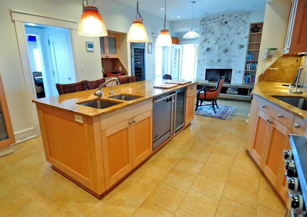 Una cocina amplia con una isla central y un comedor junto a la chimenea de piedra.
