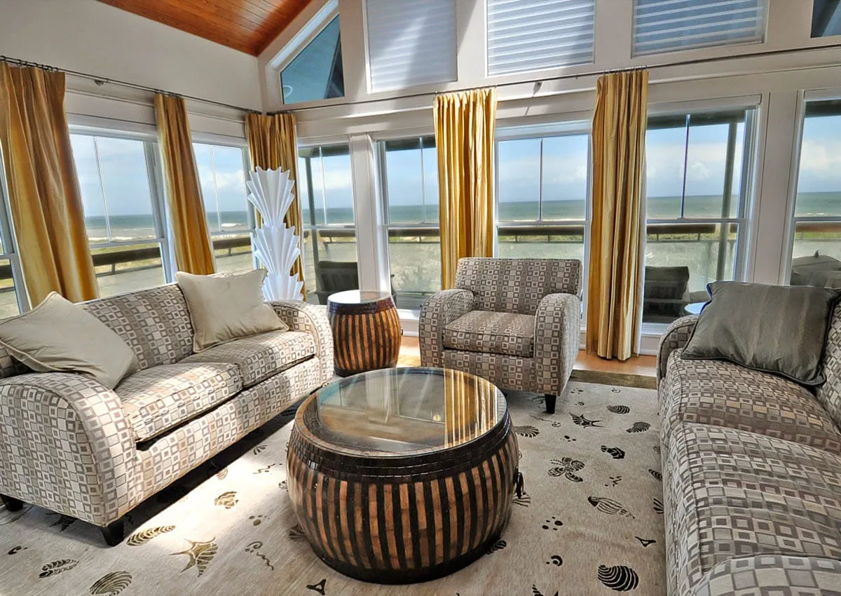 Una sala luminosa con asientos estampados y grandes ventanas con vistas al agua.