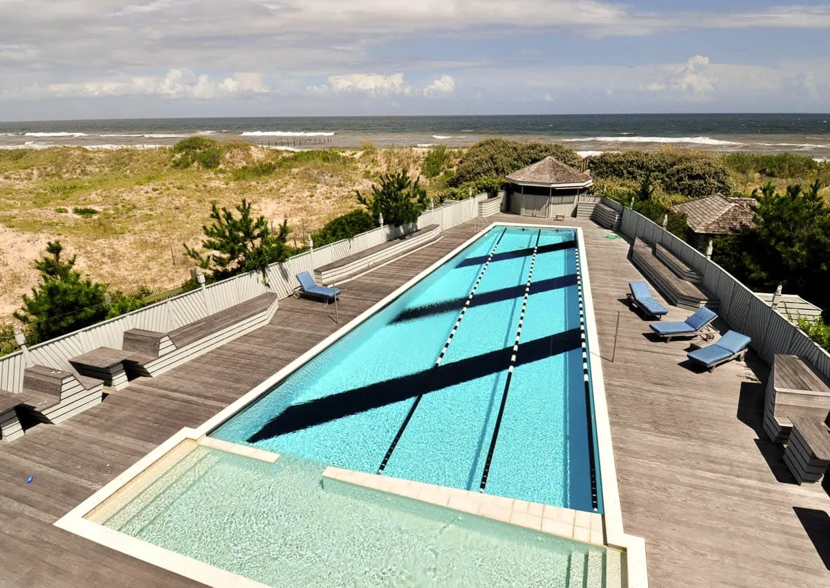 Una larga piscina al aire libre y su terraza dan a las dunas y al océano.