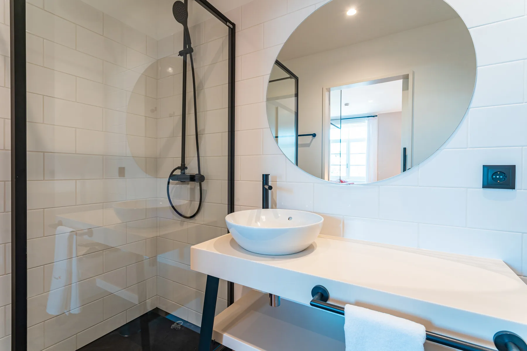A tiled bathroom with a glass shower, wall mirror, and basin.