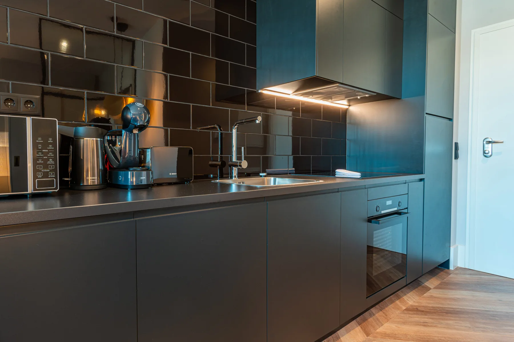 A modern kitchen with dark cabinets and appliances along the counter.