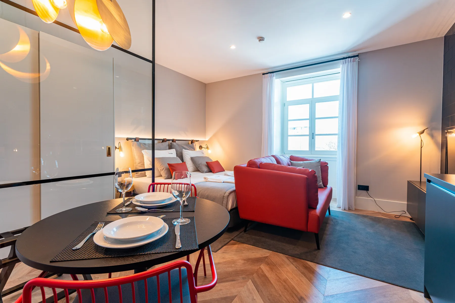 A studio living area combines a dining table, seating, and a bright window.