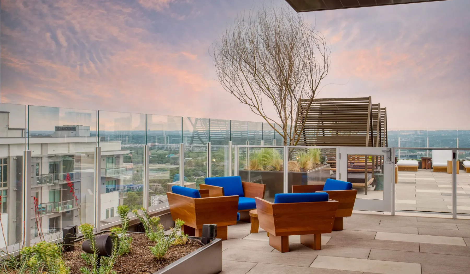 A rooftop terrace with outdoor seating and glass railings overlooks the city.