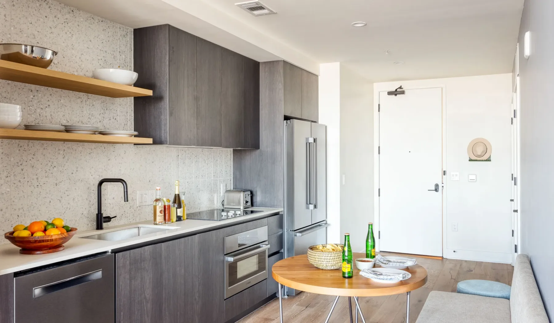 A modern kitchen with dark cabinetry, a countertop, and a dining table.
