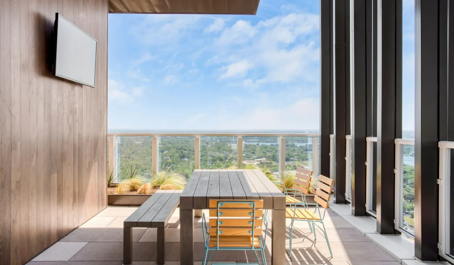An outdoor dining area with a long table and seating overlooks a green landscape.