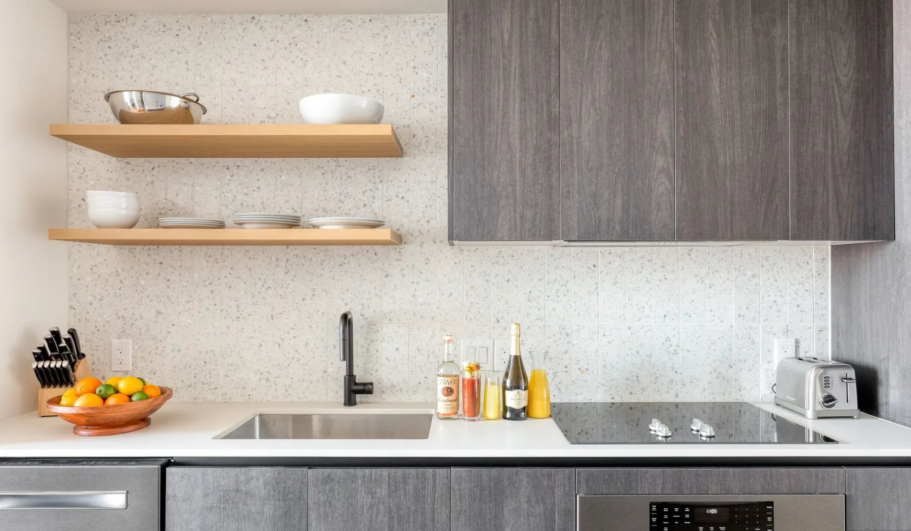 A modern kitchen with open shelves, a sink, and a countertop.