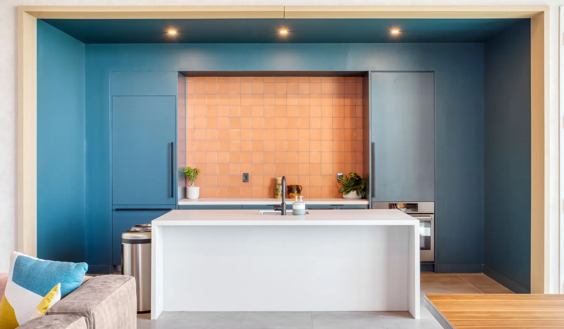 A modern kitchen with a white island and a tiled backsplash.