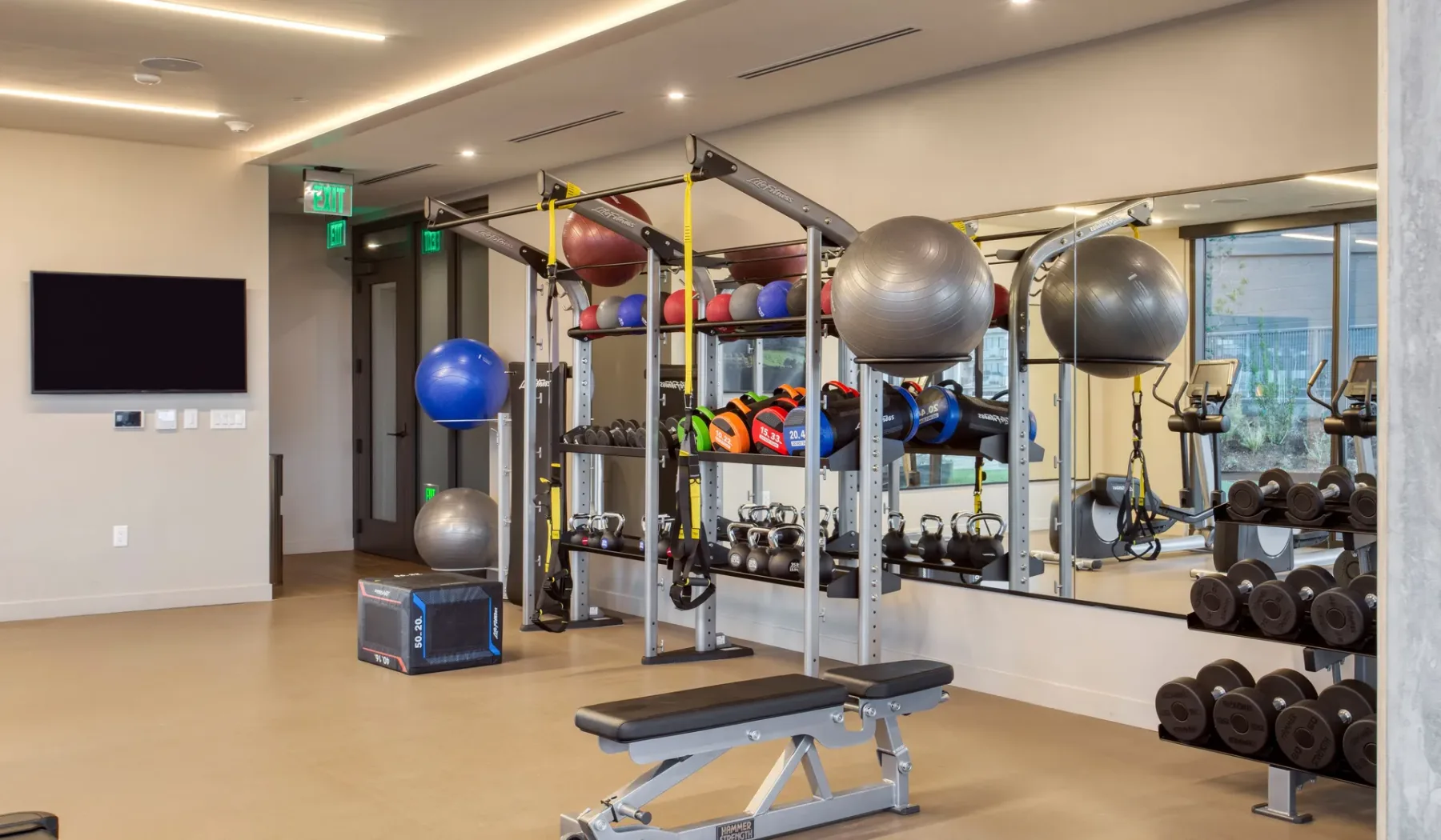 A gym with exercise equipment, weights, and a workout bench.