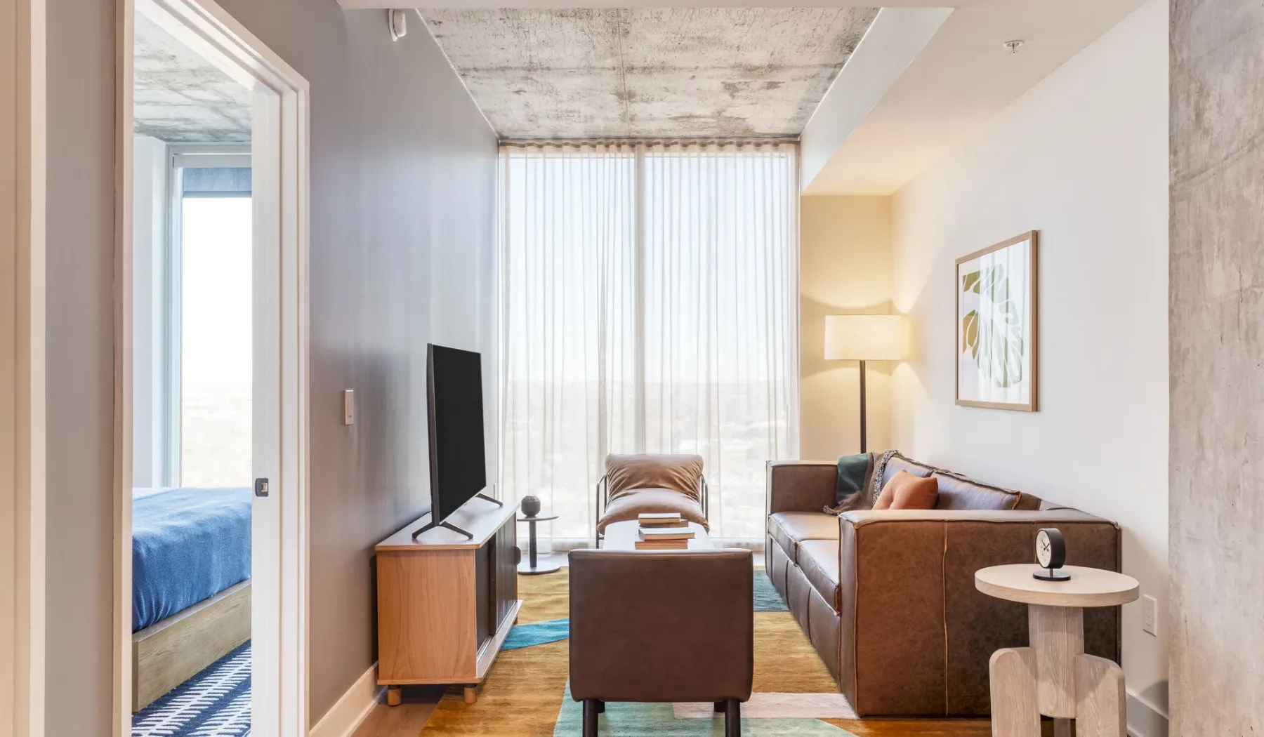 A bright living room with seating, a television, and tall windows.