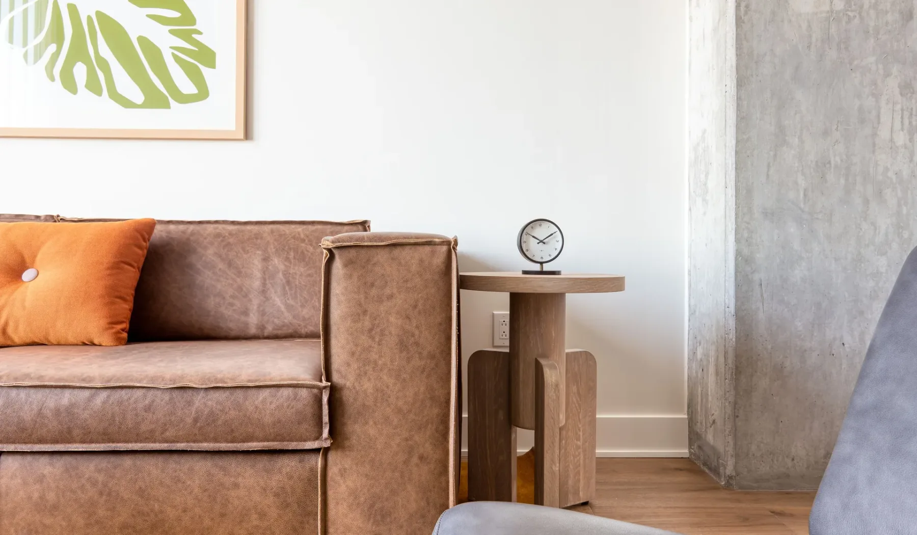 Living room with brown seating, a side table, and framed botanical artwork.