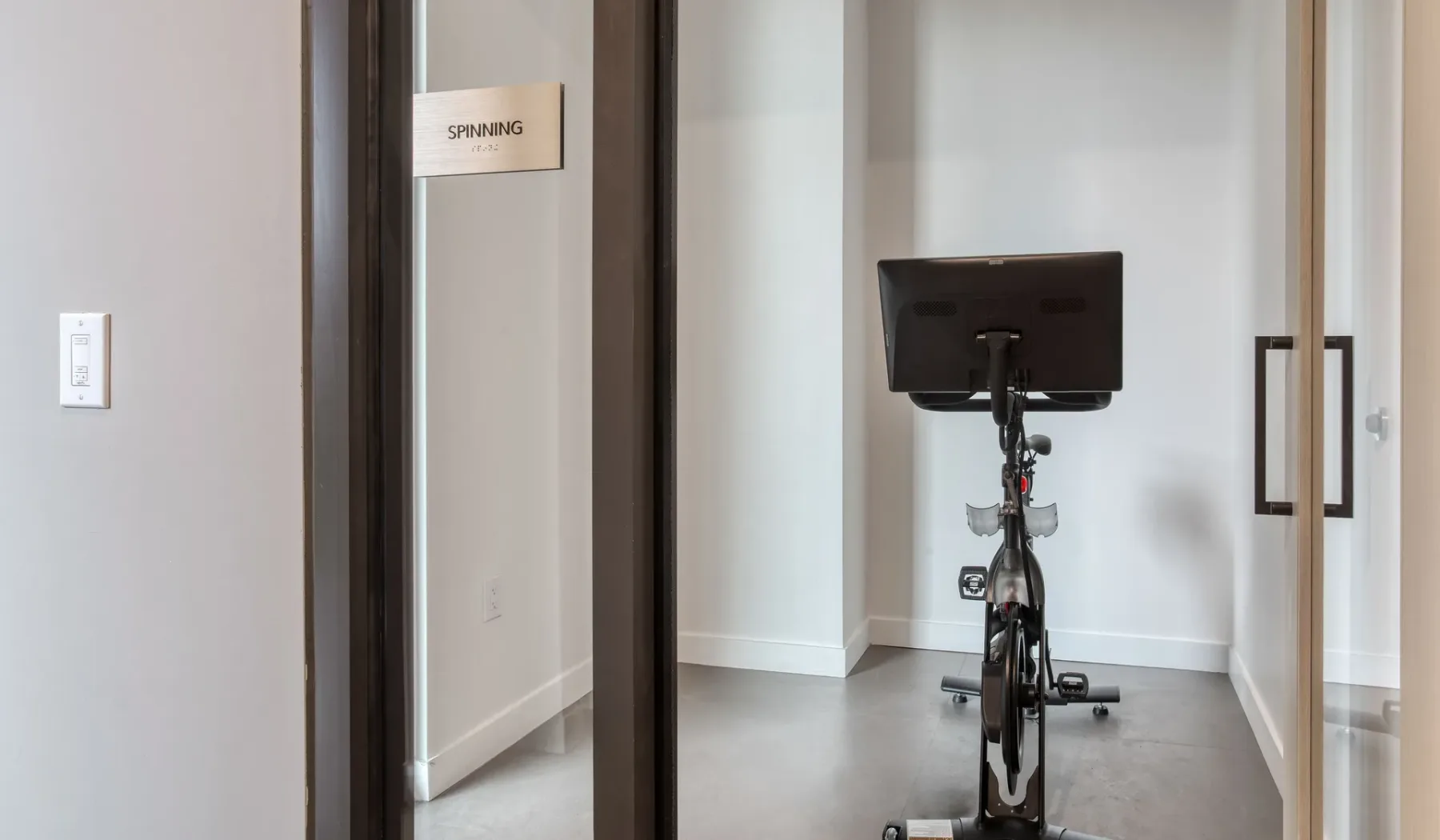 A compact exercise room with a stationary bike and wall mirror.