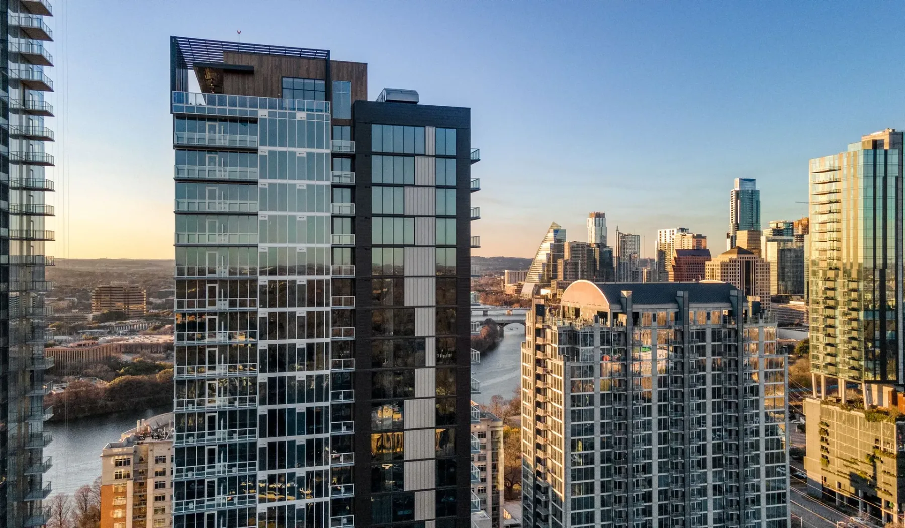 A city skyline of modern high-rise buildings beside a river.