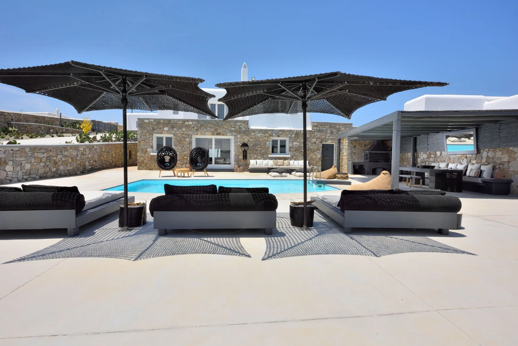 An outdoor pool terrace with shaded lounge seating and a covered dining area.