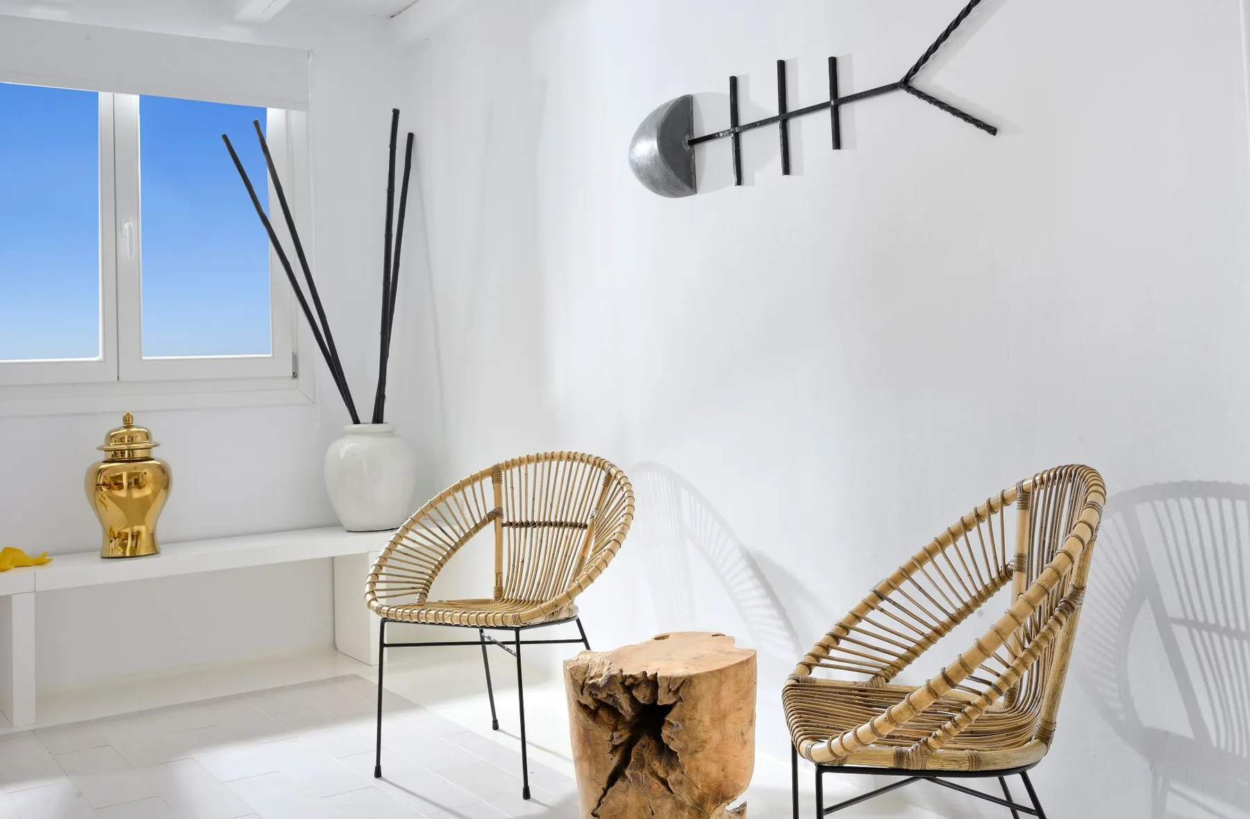 A bright sitting area with woven seating and a sculptural wall clock.