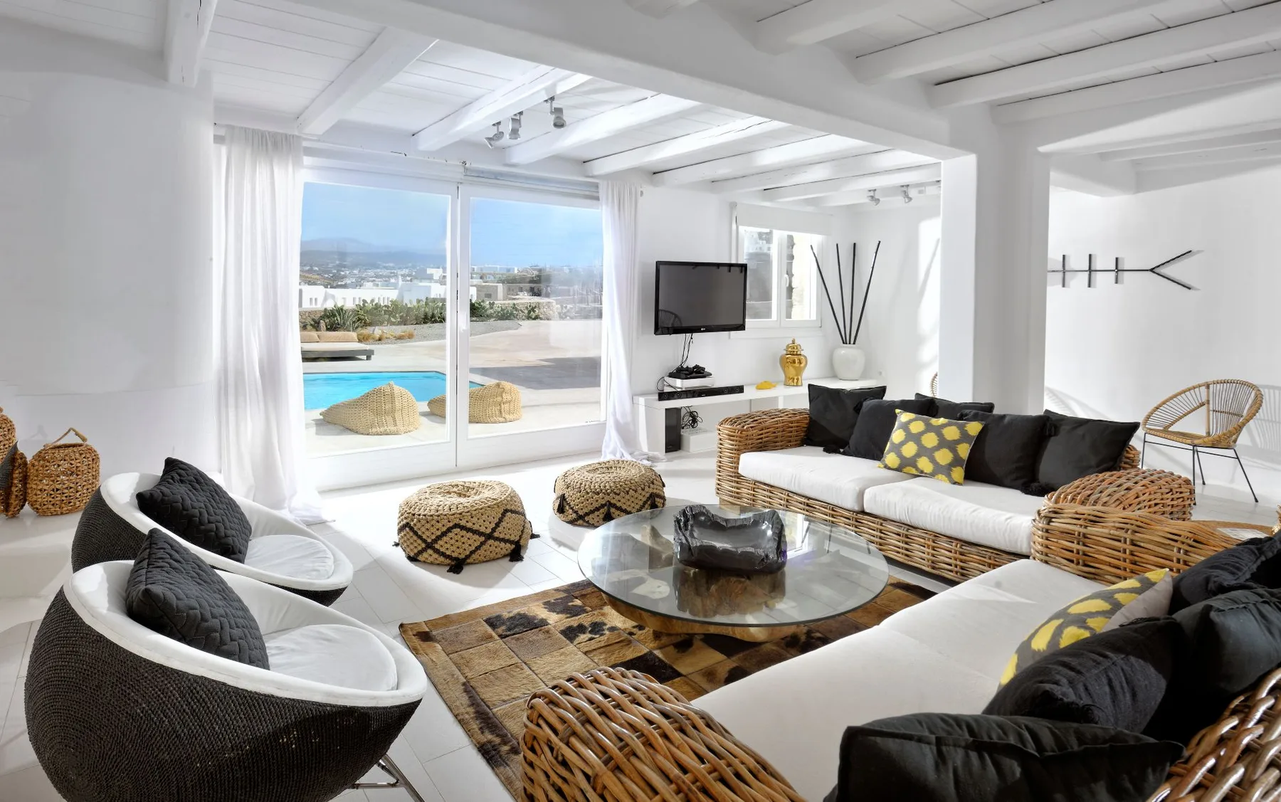 Bright living room with seating around a glass coffee table and views of a pool.