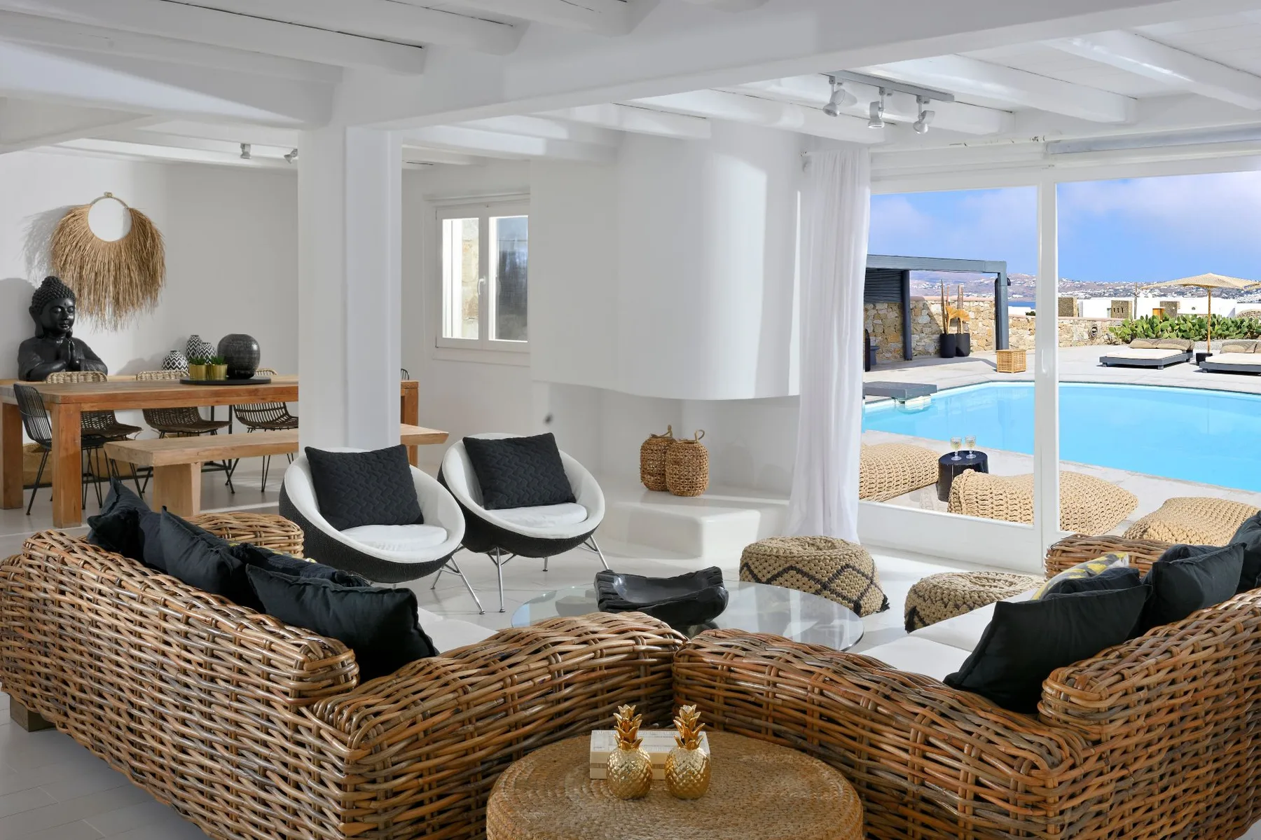 A bright living room with wicker seating and views of a swimming pool.