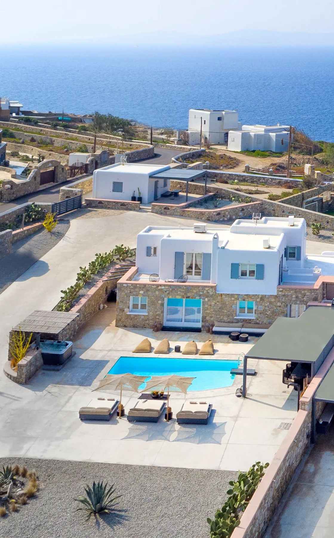 Modern villas with a swimming pool overlook the sea.