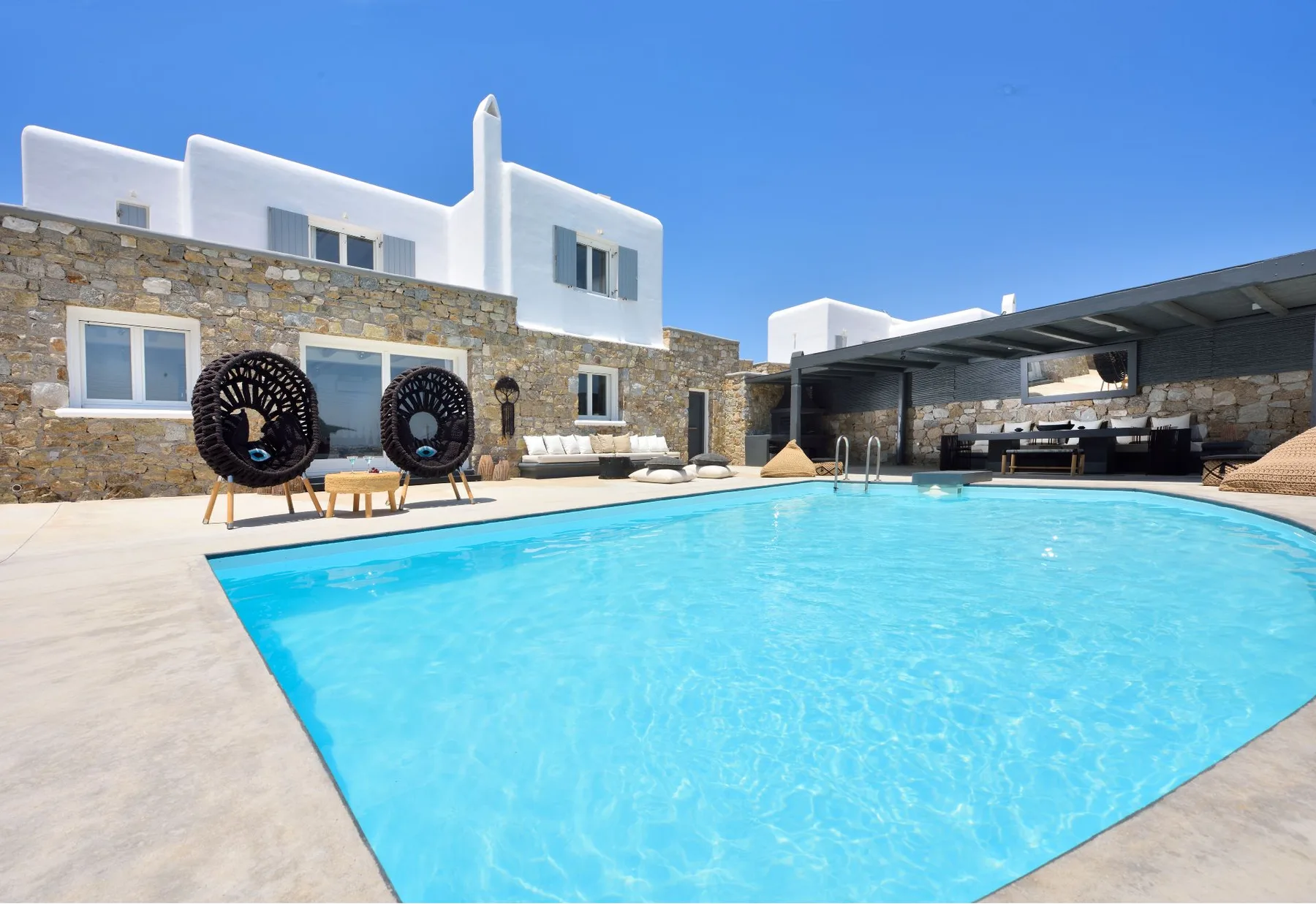 A swimming pool fills the courtyard beside a stone-faced villa.