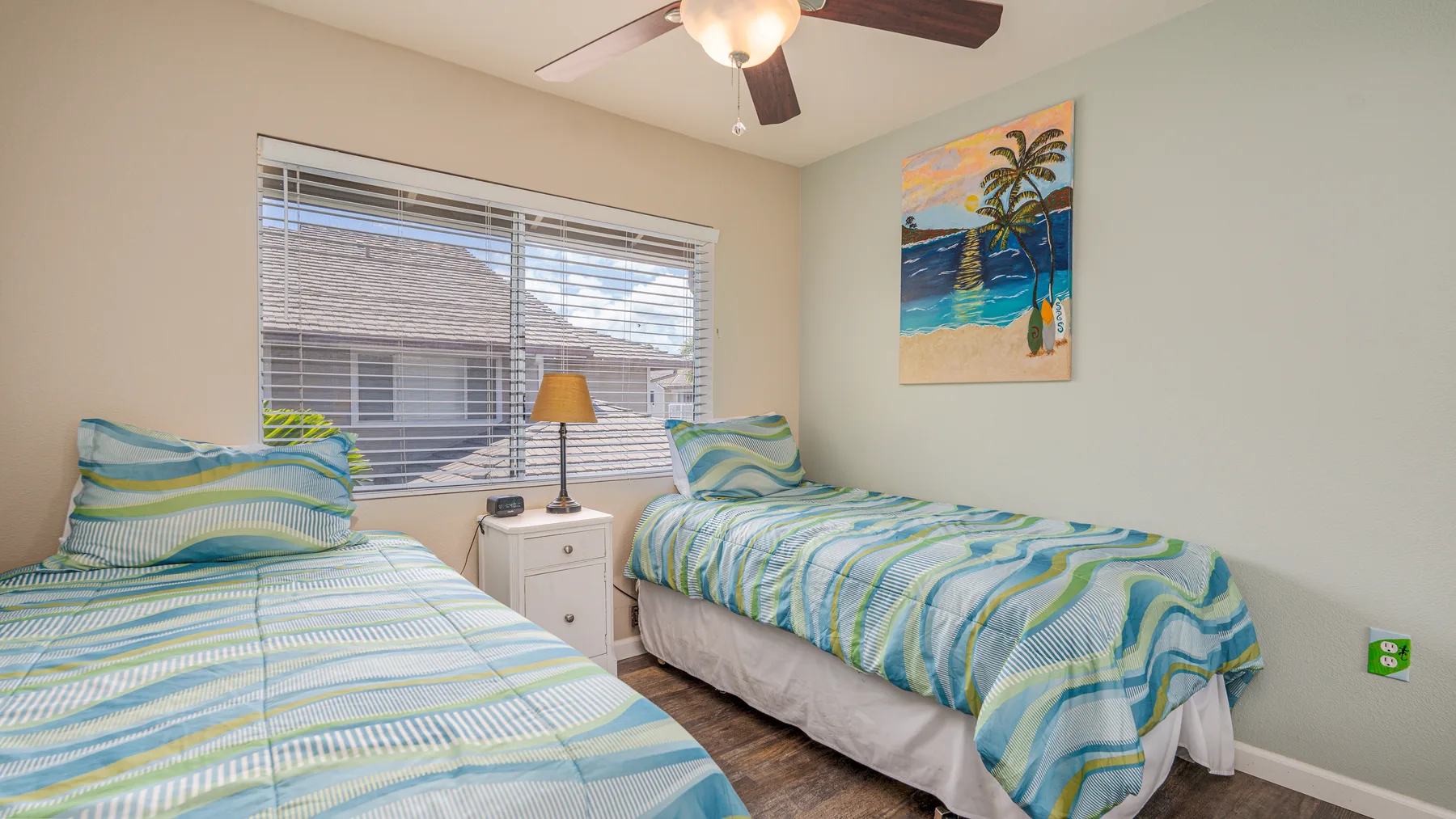 Un dormitorio con dos camas cubiertas con ropa de cama a rayas azules y verdes.