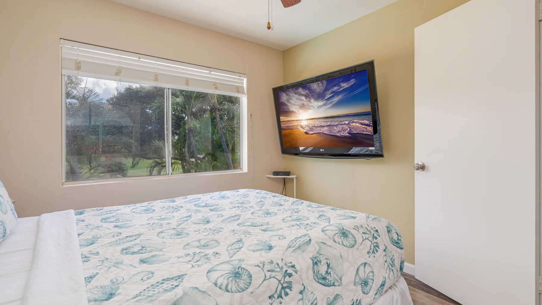 Un dormitorio con una cama junto a una ventana y un televisor en la pared.