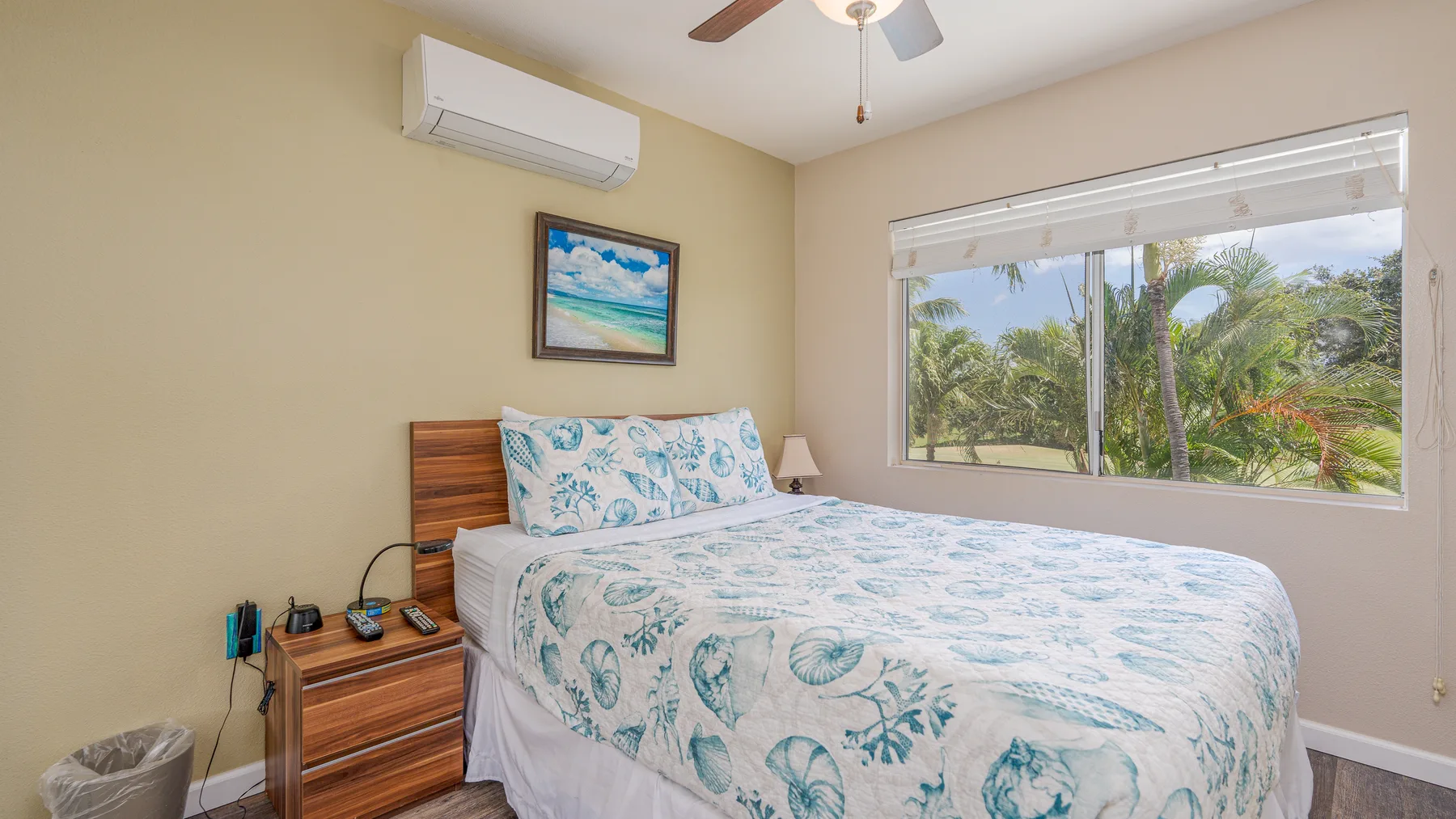 Un dormitorio con una cama cubierta con ropa de cama estampada en azul claro junto a una ventana grande.
