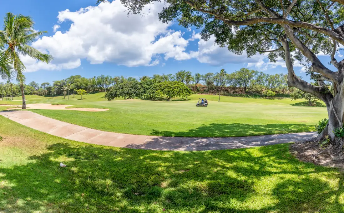 Un amplio campo de golf verde se extiende bajo un cielo parcialmente nublado.
