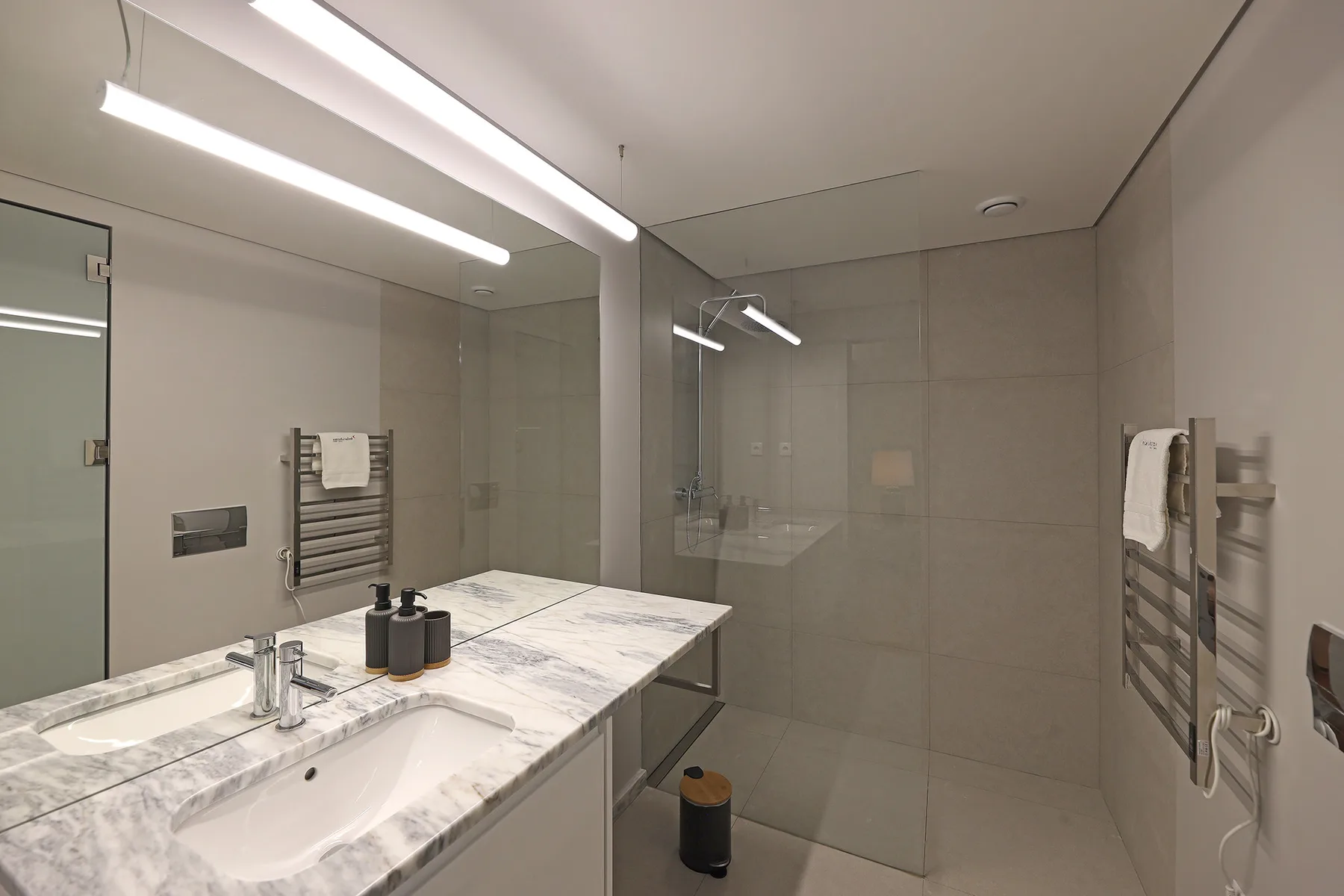 A modern bathroom with a wide sink counter and a glass shower area.