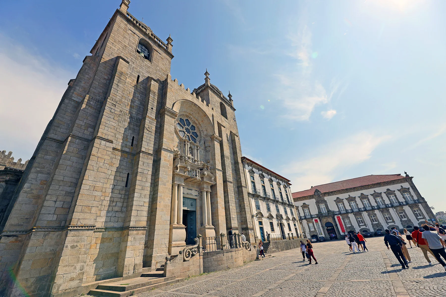 A stone church façade faces a broad paved plaza with pedestrians.