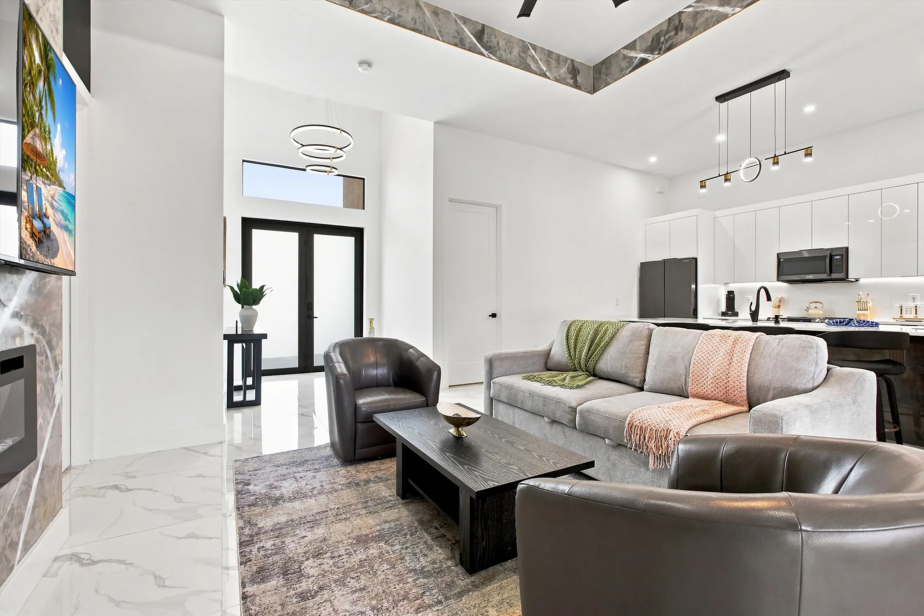 A bright living room with a sectional sofa and a kitchen in the background.