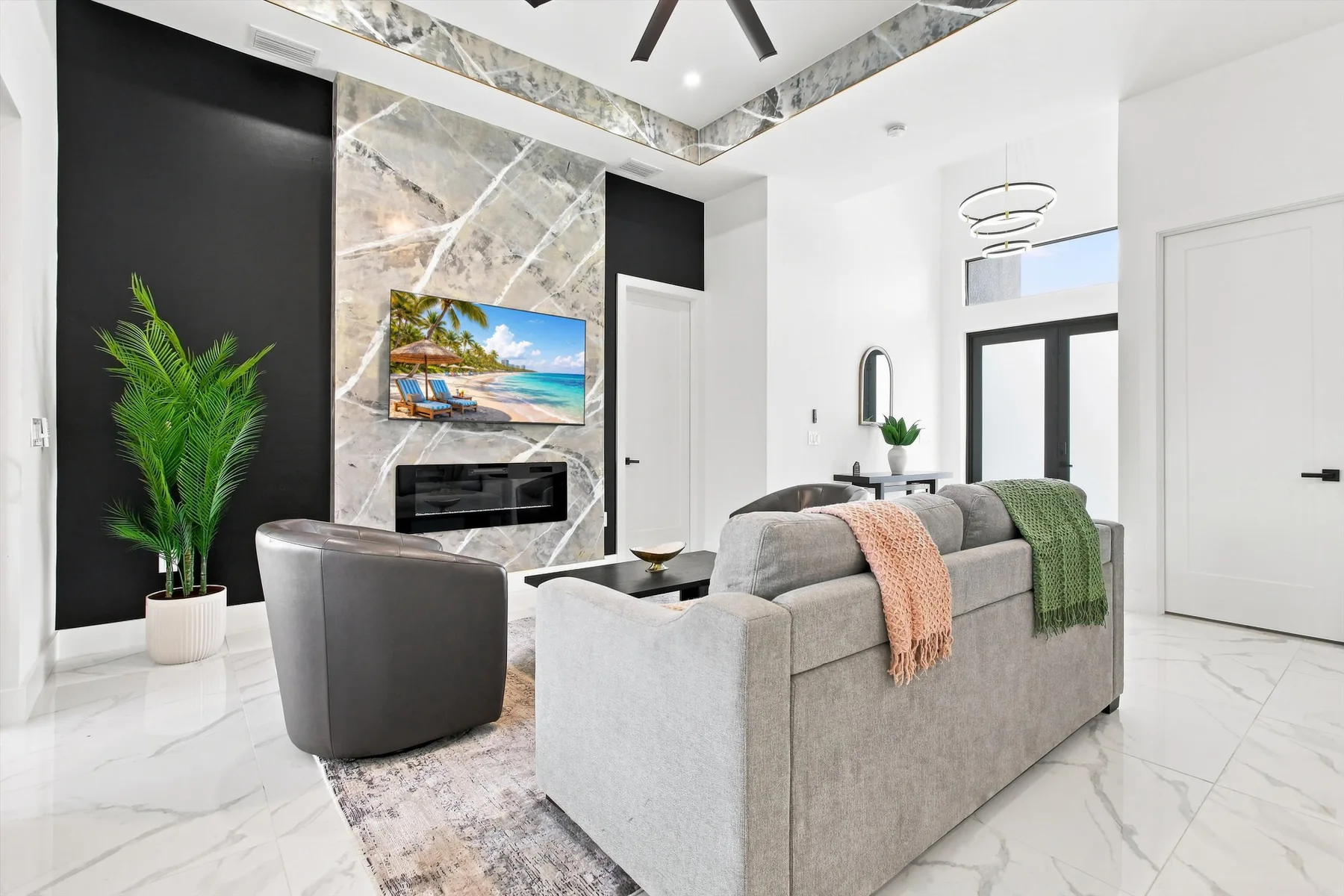 A bright living room with seating facing a marble feature wall and television.