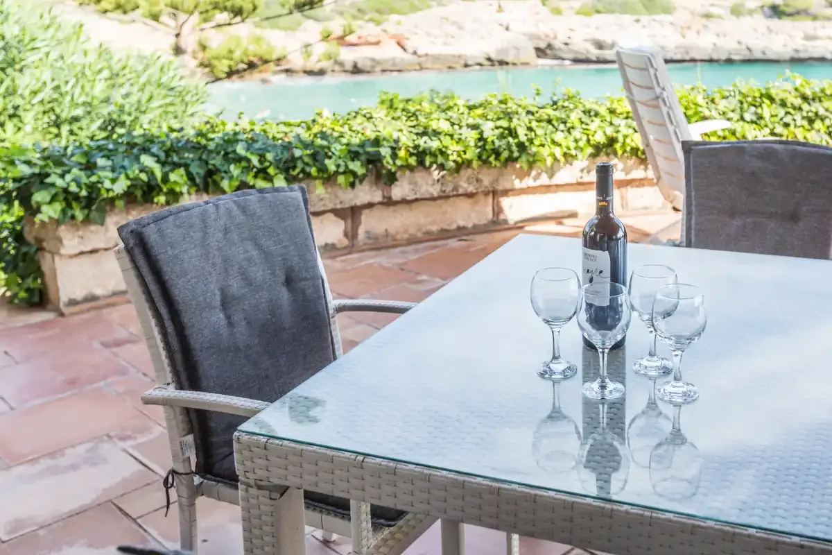 An outdoor patio dining area with a glass table and a view of the water.