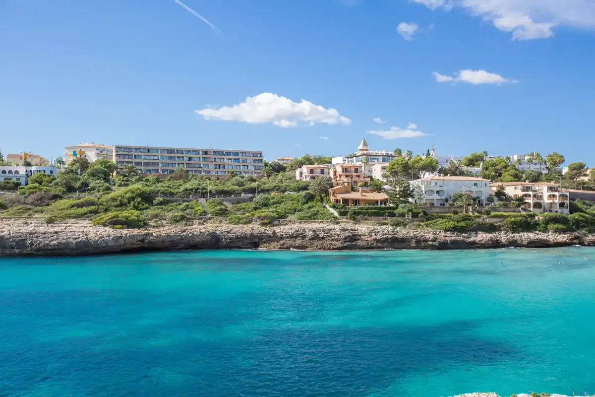 A turquoise bay borders a rocky coastline with buildings among the greenery.
