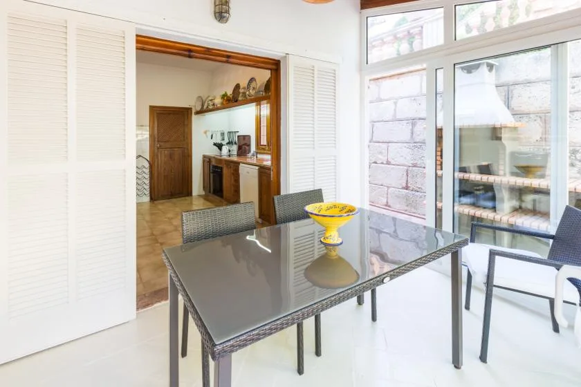 A bright dining area with a glass-top table beside large windows.