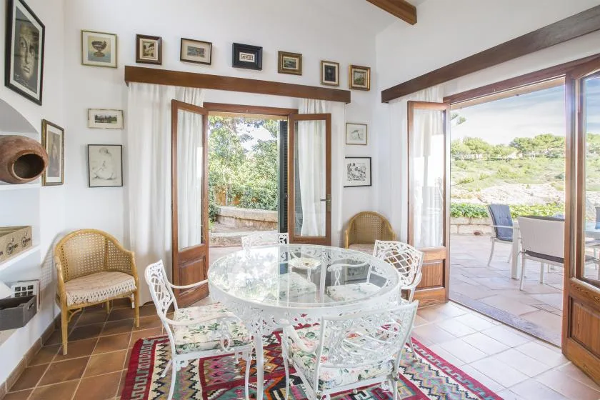 A bright dining area with a glass table and doors opening onto a terrace.