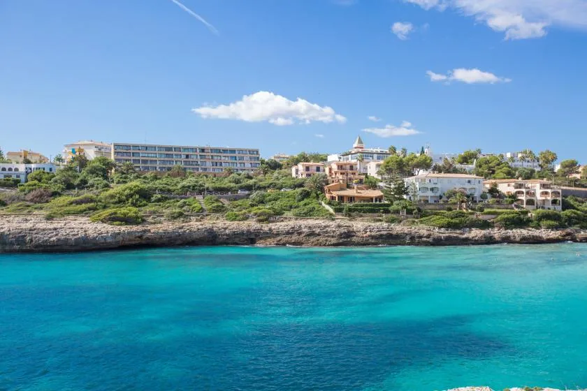 A coastal resort sits among greenery above turquoise water.