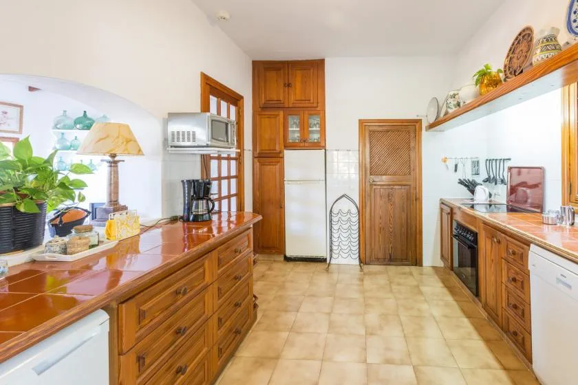 A bright kitchen with wooden cabinetry and a tiled floor.