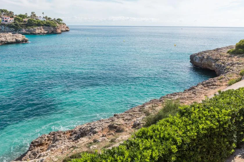 Coastal cove with clear turquoise water and rocky shoreline.