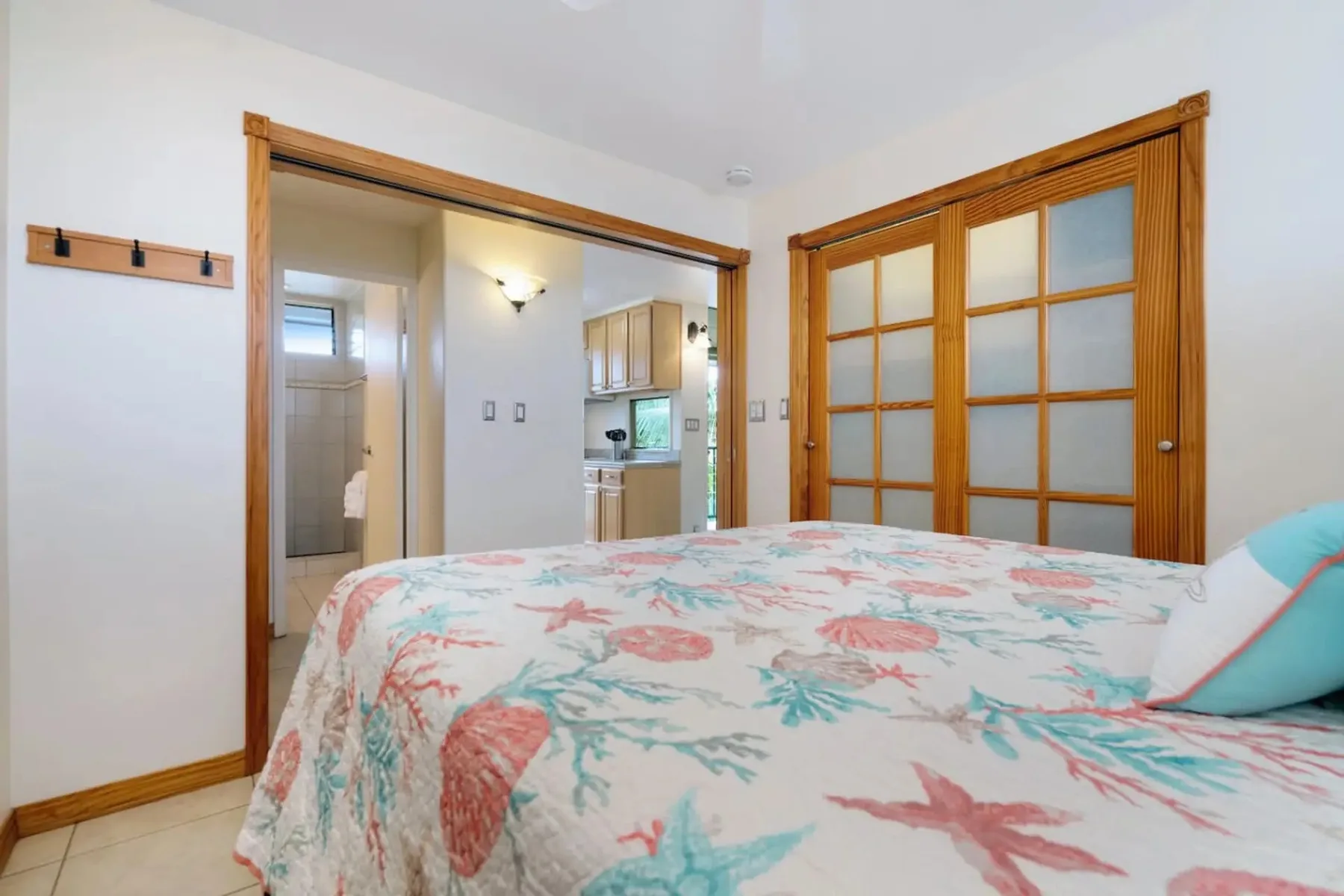 Dormitorio con una colcha floral y puertas corredizas de madera.