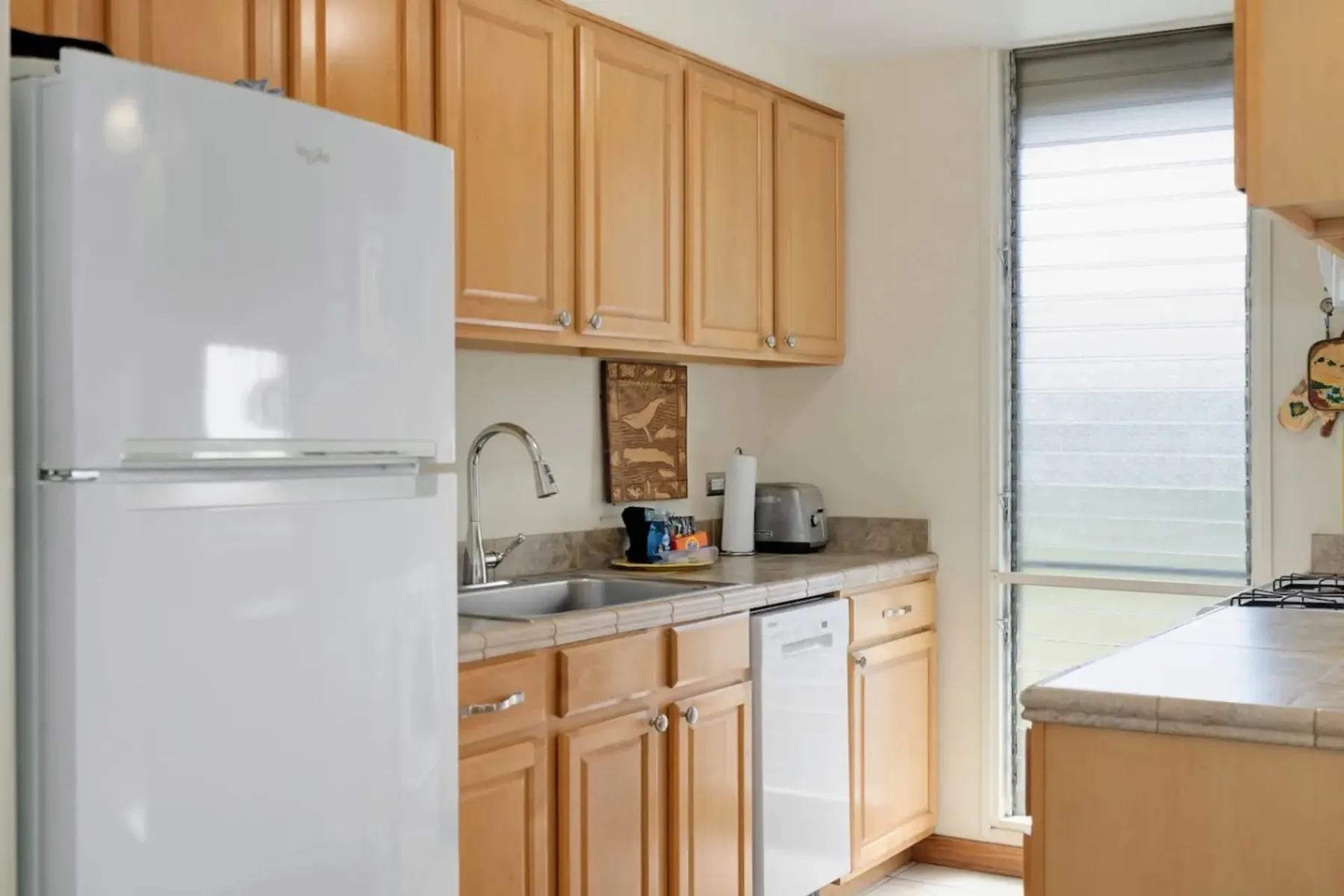 Una cocina con gabinetes de madera, un refrigerador y un fregadero.