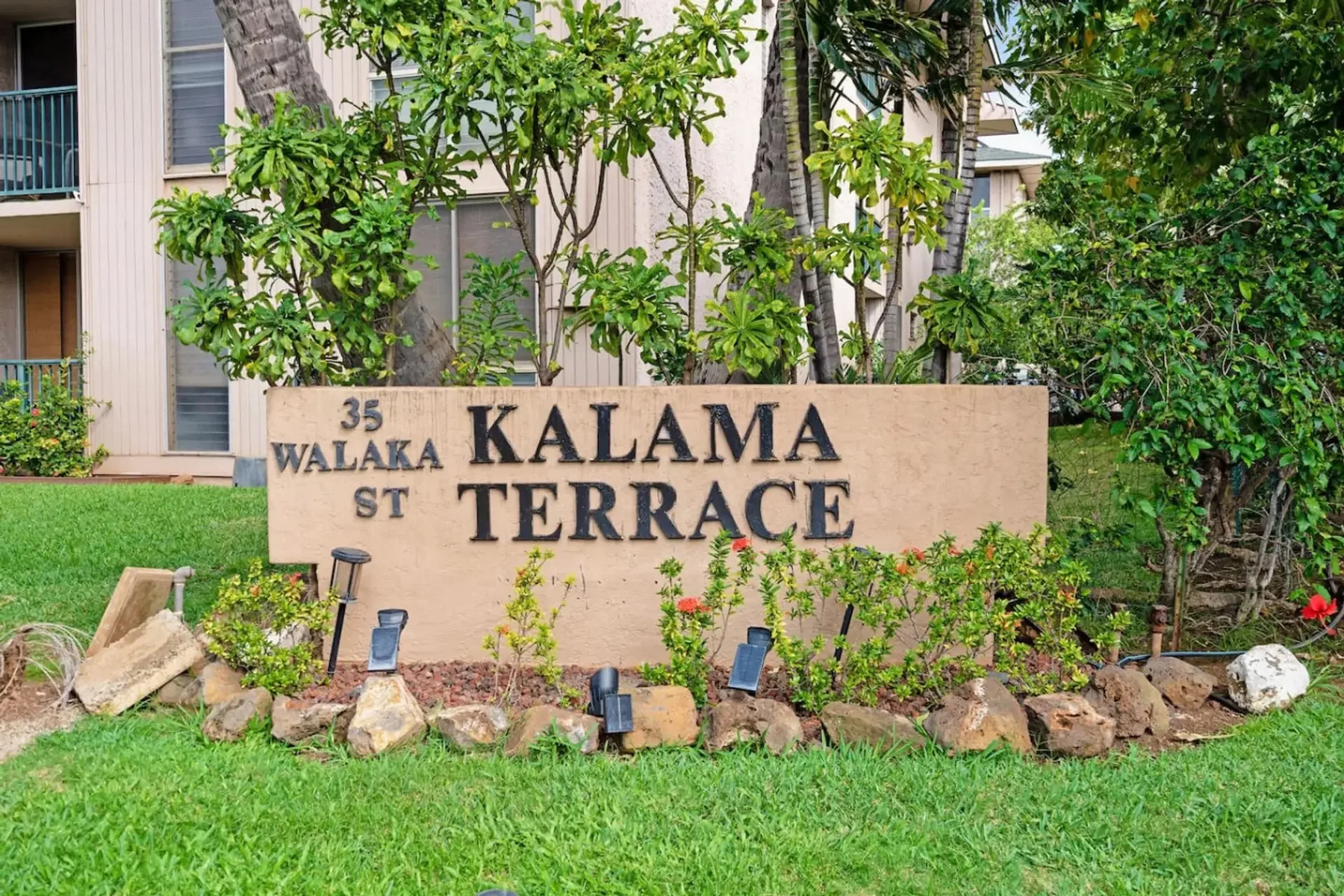 Un letrero ajardinado de Kalama Terrace está junto a un edificio de apartamentos.