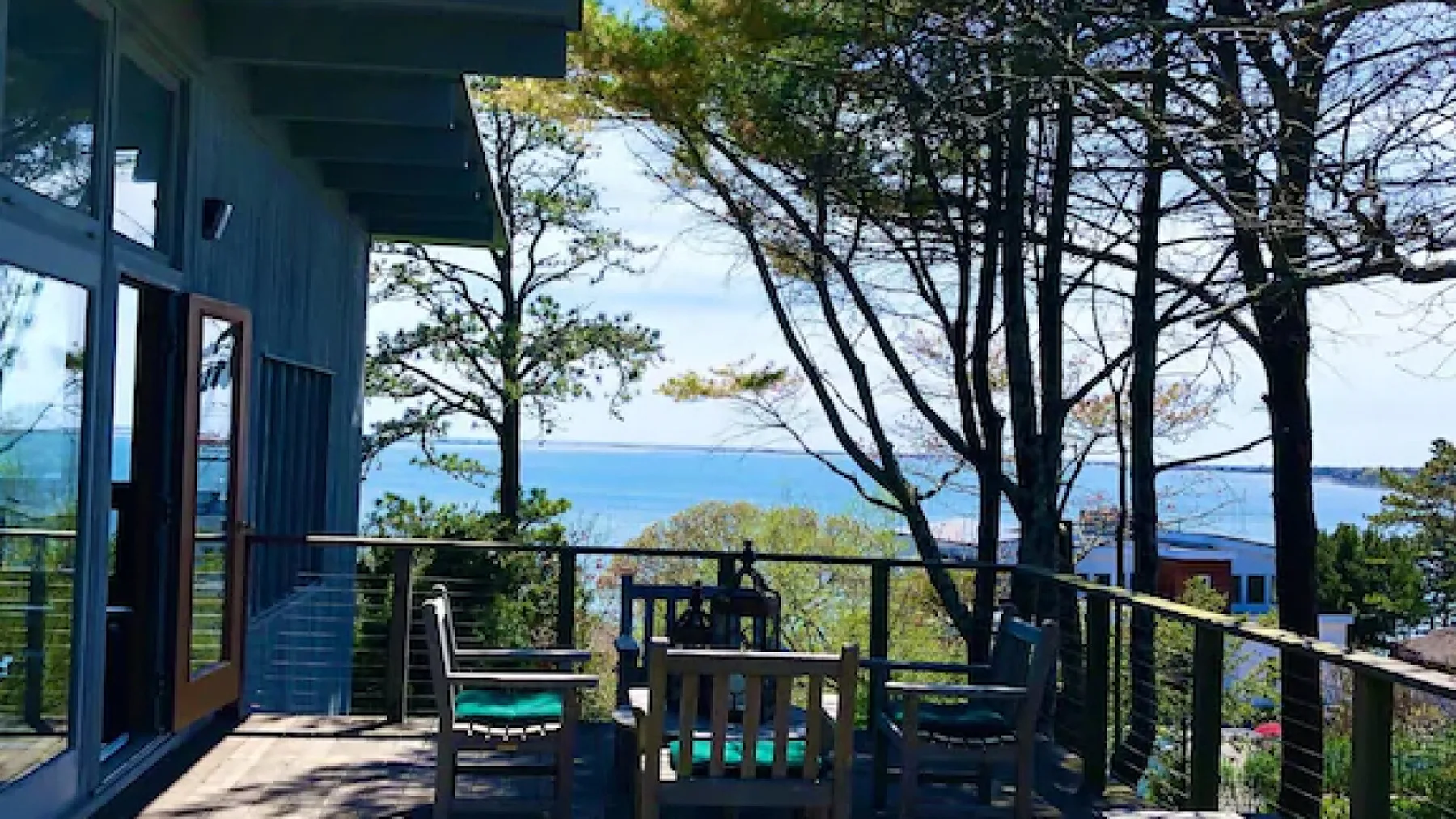 Una terraza con asientos ofrece vistas de árboles y una extensión de agua.