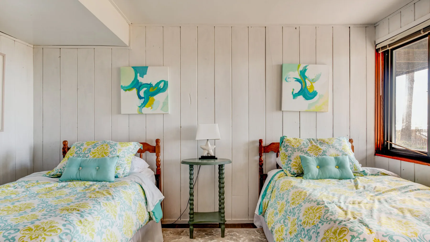 Un dormitorio luminoso con dos camas individuales y ropa de cama floral colorida.